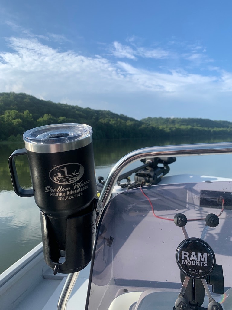Shallow Water Fishing Adventures branded tumbler on the boat with river views