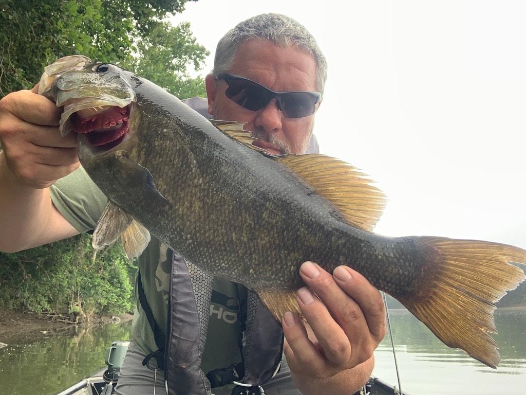 Angler holding trophy smallmouth bass on guided fishing trip